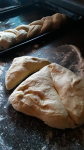 One loaf of braided dough, with 3 pieces cut and ready to be assembled.